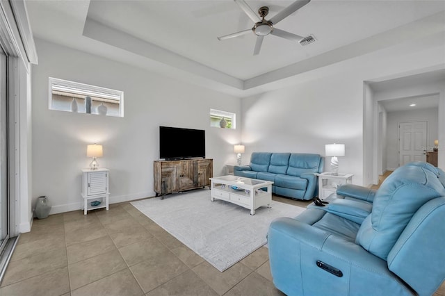 living room with a raised ceiling, visible vents, and light tile patterned floors