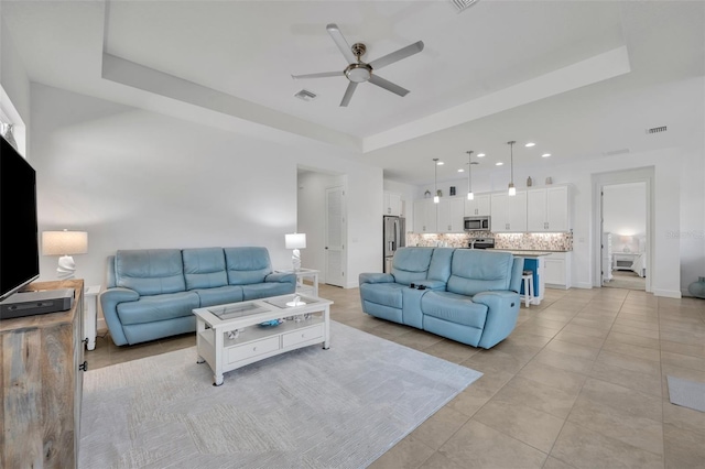 living room featuring a raised ceiling and visible vents