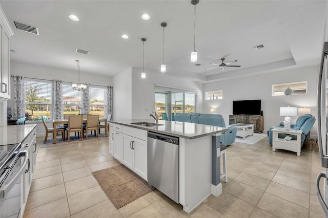 kitchen featuring a tray ceiling, visible vents, appliances with stainless steel finishes, white cabinetry, and a sink