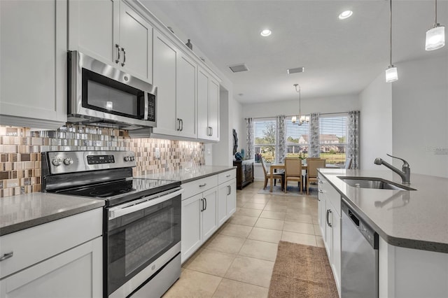 kitchen featuring light tile patterned floors, visible vents, decorative backsplash, stainless steel appliances, and a sink