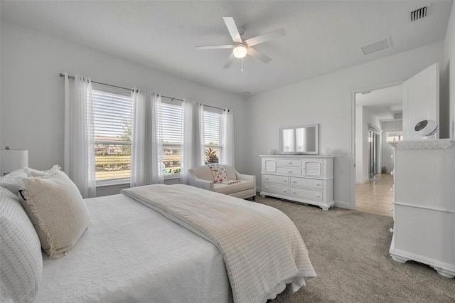 bedroom with light carpet, ceiling fan, visible vents, and baseboards