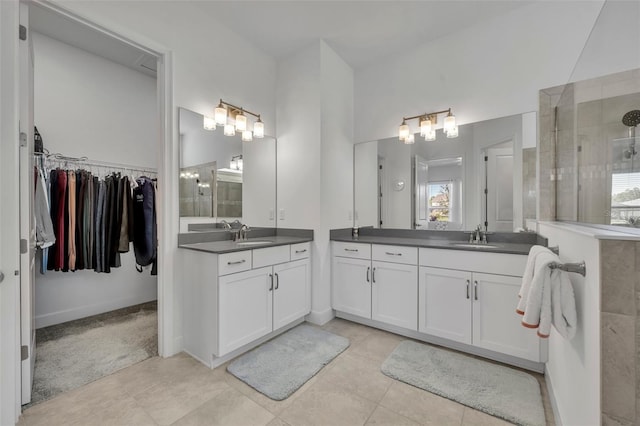 full bath featuring two vanities, a spacious closet, a sink, tiled shower, and tile patterned floors