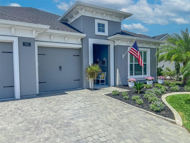 585 Mosaic Blvd, Daytona Beach, FL 32124 - view of front of property featuring decorative driveway, a garage, roof with shingles, and stucco siding
