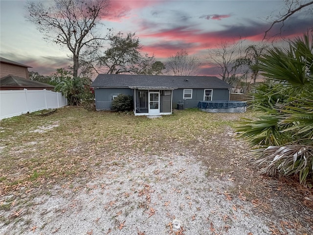 back of house with a sunroom, fence, and a lawn