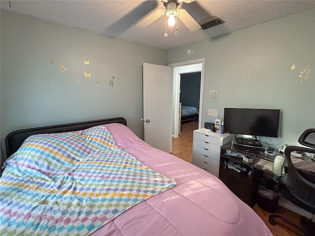 bedroom with a ceiling fan, visible vents, and a textured ceiling