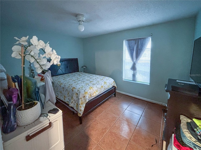 tiled bedroom with a textured ceiling, a ceiling fan, and baseboards