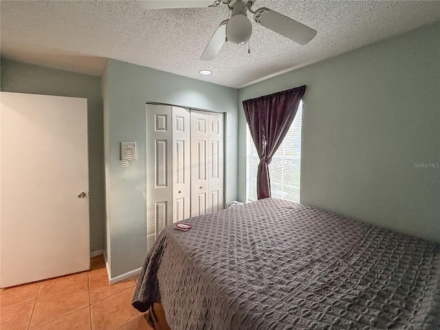 bedroom with light tile patterned floors, ceiling fan, a textured ceiling, and a closet