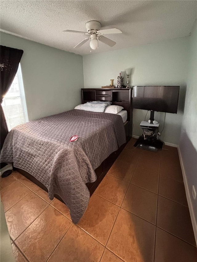 bedroom featuring a textured ceiling, dark tile patterned flooring, a ceiling fan, and baseboards