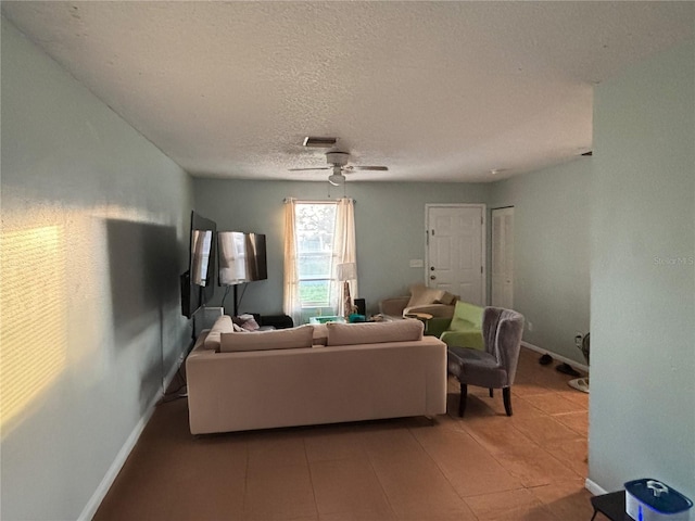 living area with light tile patterned floors, baseboards, visible vents, a ceiling fan, and a textured ceiling