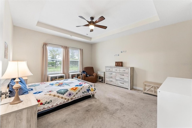 carpeted bedroom featuring a tray ceiling and a ceiling fan