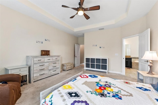bedroom with light carpet, a raised ceiling, baseboards, and a ceiling fan