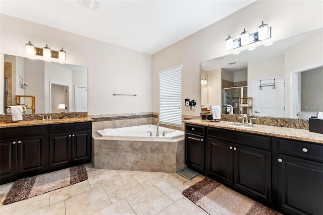 bathroom featuring a stall shower, a bath, two vanities, and tile patterned flooring
