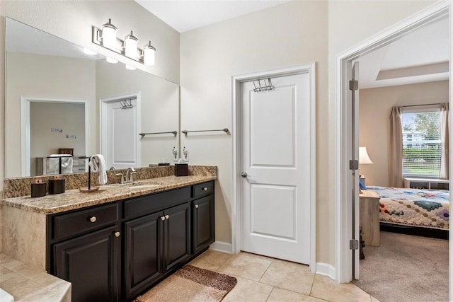 ensuite bathroom featuring tile patterned floors, baseboards, and vanity