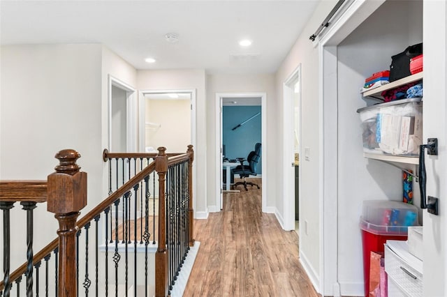 corridor with light wood finished floors, baseboards, and recessed lighting