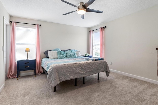 bedroom with light colored carpet, baseboards, a ceiling fan, and a textured ceiling