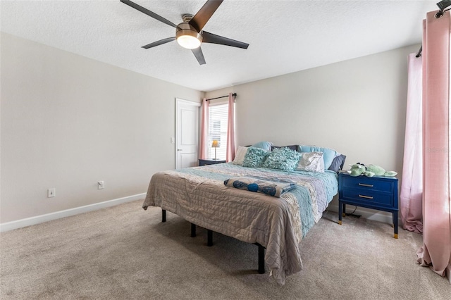 carpeted bedroom with a textured ceiling, baseboards, and ceiling fan