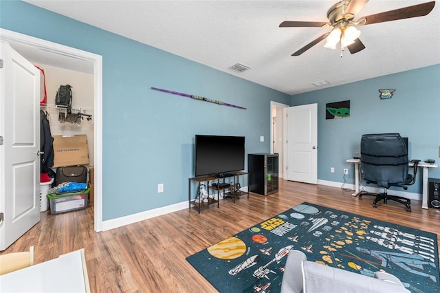 office area featuring wood finished floors, a ceiling fan, baseboards, and a textured ceiling