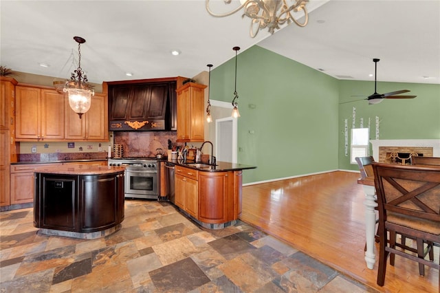 kitchen featuring appliances with stainless steel finishes, open floor plan, custom exhaust hood, a fireplace, and a sink