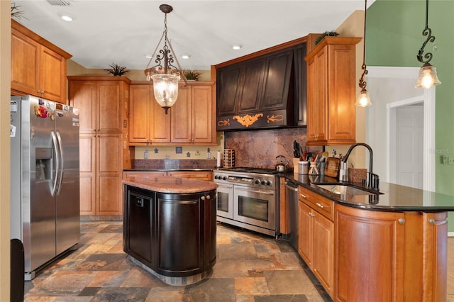 kitchen featuring range hood, appliances with stainless steel finishes, stone finish flooring, a sink, and a peninsula