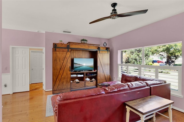 living room featuring a ceiling fan, light wood-type flooring, visible vents, and a healthy amount of sunlight