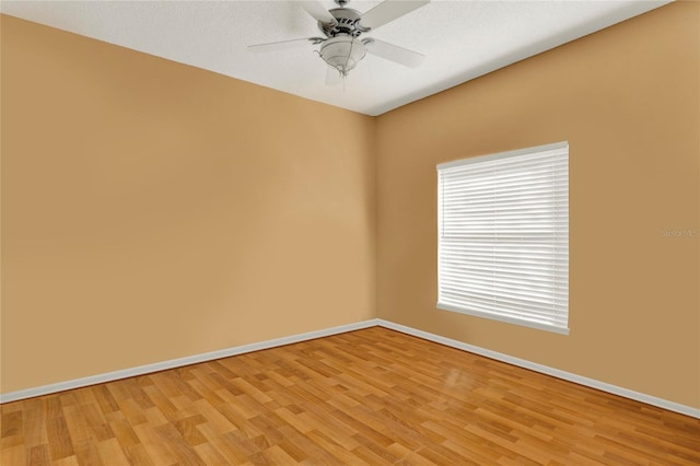 spare room featuring ceiling fan, light wood finished floors, and baseboards