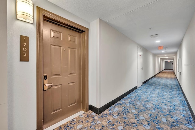 hall with a textured ceiling and baseboards