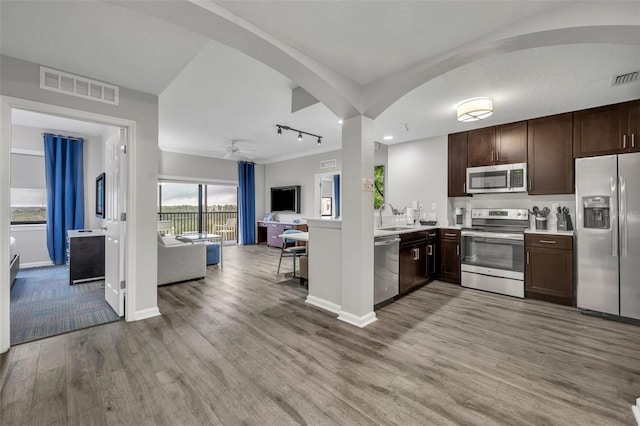 kitchen with arched walkways, a sink, visible vents, open floor plan, and appliances with stainless steel finishes