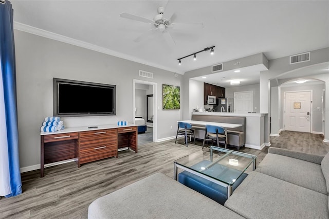 living area featuring arched walkways, light wood finished floors, and visible vents