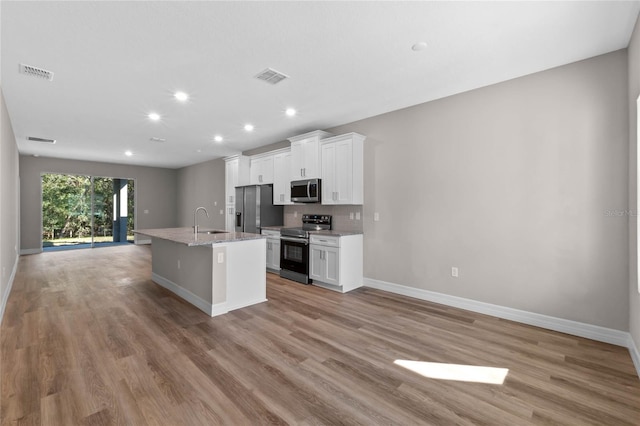 kitchen with visible vents, an island with sink, stainless steel appliances, white cabinetry, and a sink