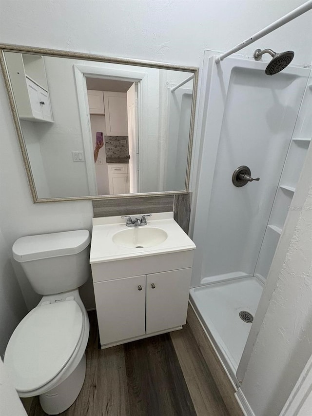 full bathroom featuring a stall shower, vanity, toilet, and wood finished floors