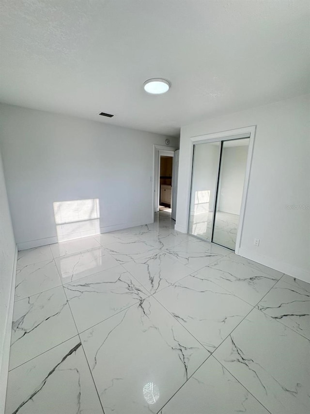 empty room with marble finish floor, visible vents, and baseboards