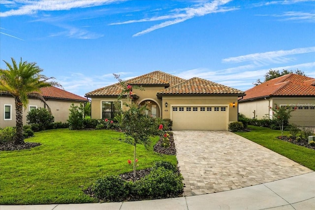 mediterranean / spanish-style house featuring an attached garage, a tile roof, decorative driveway, stucco siding, and a front yard