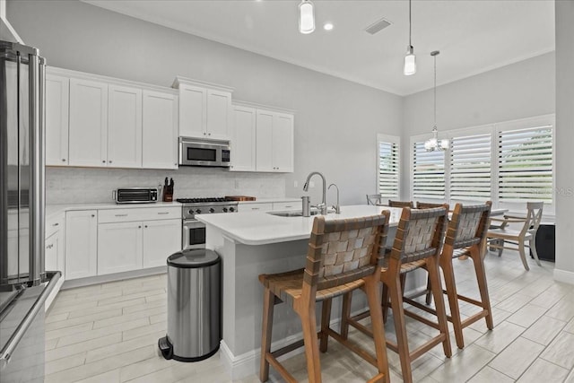 kitchen featuring premium appliances, a sink, light countertops, a center island with sink, and pendant lighting