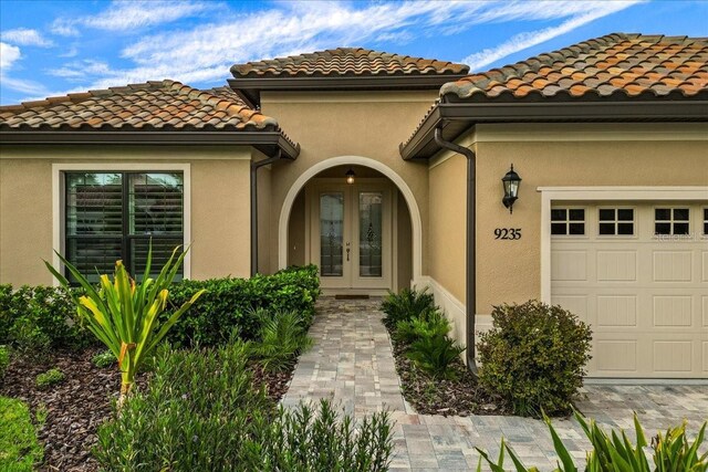 9235 San Jose Blvd, Howey In The Hills, FL 34737 - entrance to property with french doors, an attached garage, stucco siding, and a tile roof