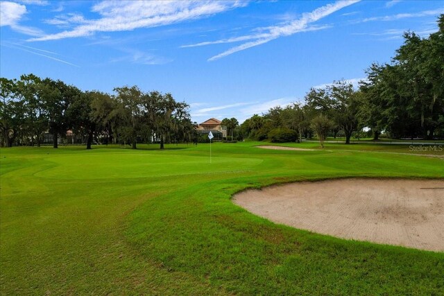 9235 San Jose Blvd, Howey In The Hills, FL 34737 - view of community with a lawn, view of golf course, a putting area, and view of wooded area