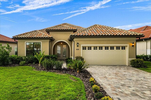 9235 San Jose Blvd, Howey In The Hills, FL 34737 - mediterranean / spanish-style house featuring stucco siding, french doors, an attached garage, and decorative driveway