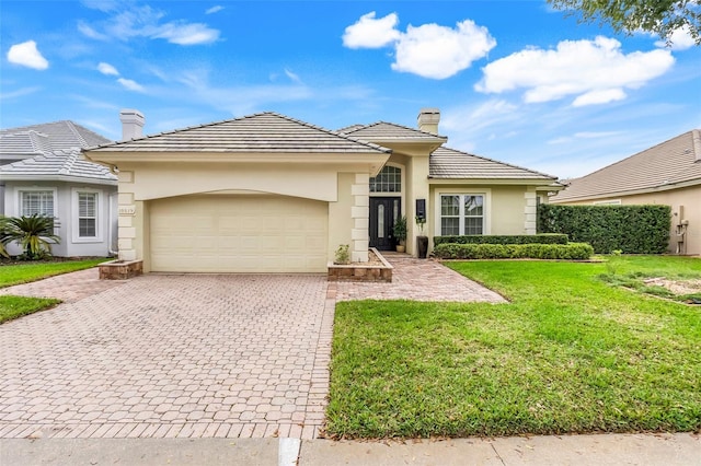 view of front of property featuring decorative driveway, a chimney, stucco siding, a garage, and a front lawn