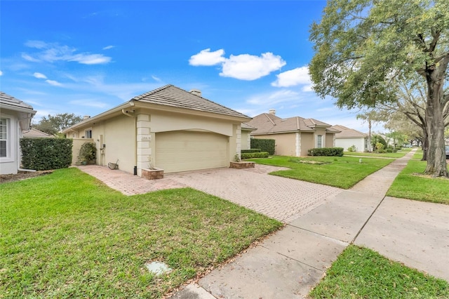 view of front facade with a garage, decorative driveway, a front lawn, and stucco siding