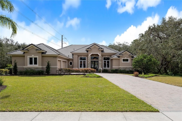 prairie-style home featuring stone siding, decorative driveway, and stucco siding