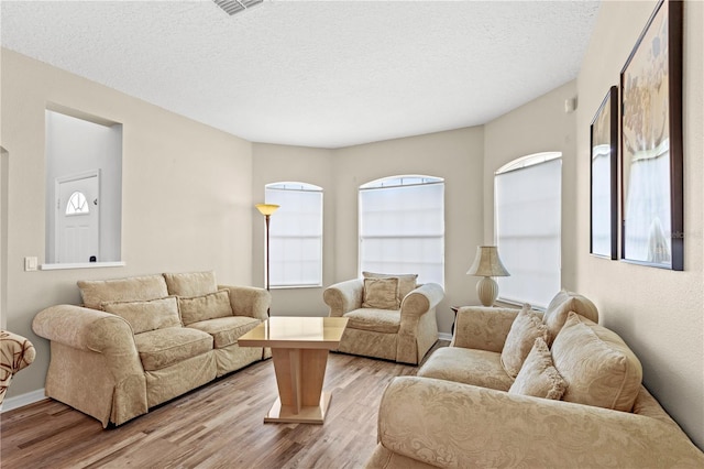 living room featuring light wood-style floors, baseboards, and a textured ceiling