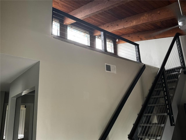 stairs with visible vents, beam ceiling, and wooden ceiling