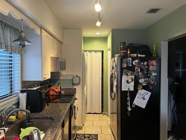 kitchen featuring visible vents, a sink, tasteful backsplash, stainless steel appliances, and dark stone counters