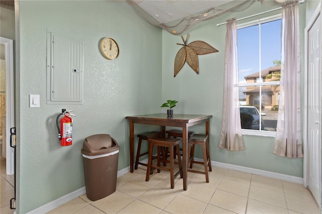 tiled dining area with electric panel and baseboards