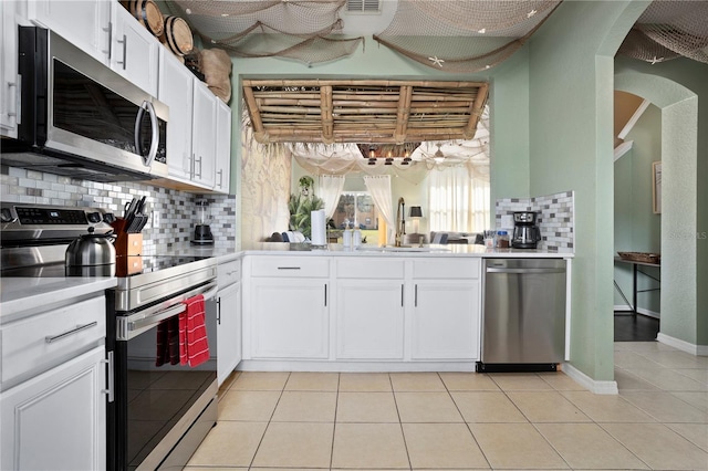 kitchen with stainless steel appliances, light countertops, white cabinetry, and light tile patterned flooring