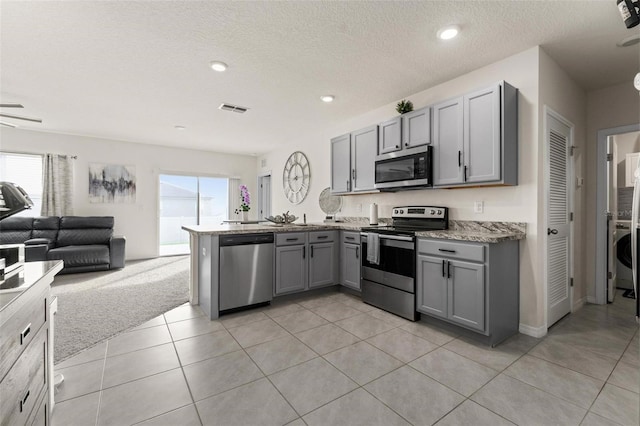 kitchen featuring visible vents, gray cabinetry, appliances with stainless steel finishes, open floor plan, and a peninsula