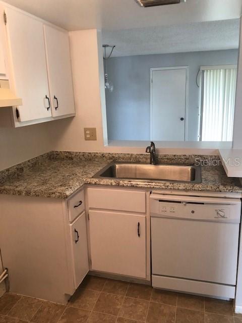 kitchen featuring white cabinetry, dishwasher, a sink, and exhaust hood