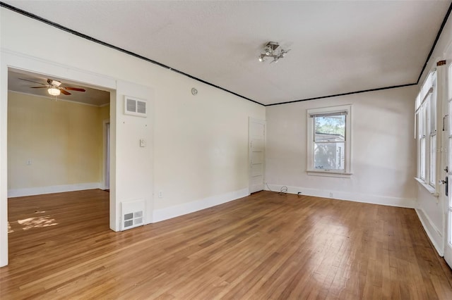 spare room with ornamental molding, baseboards, visible vents, and light wood finished floors