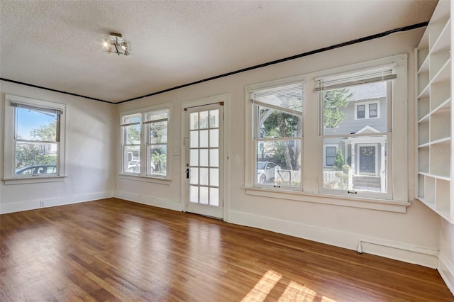 spare room featuring a textured ceiling, wood finished floors, and baseboards