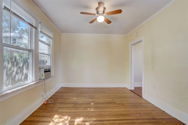 spare room with ceiling fan, ornamental molding, light wood-type flooring, and baseboards