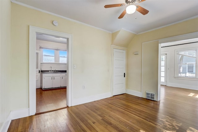 interior space with ornamental molding, hardwood / wood-style floors, visible vents, and baseboards